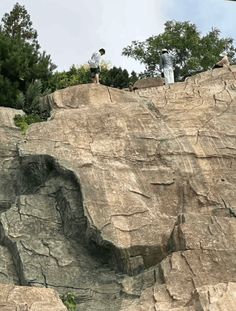 大连一跨海大桥观景台有游客翻栏杆踩空心造景石拍照，当地回应